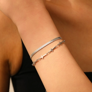 Détail d'un bracelet double couche en argent avec chaîne serpent et petits pendentifs croix
