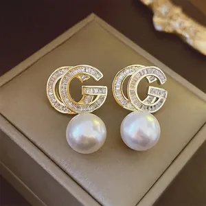 Luxurious gold-plated double G logo earrings with crystal pavé and white drop pearls