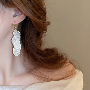 Close-up of iridescent seashell disc tassel earrings with gold hooks on a model