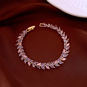 Macro view of golden wheat leaf bracelet with purple and pink zircon on silk