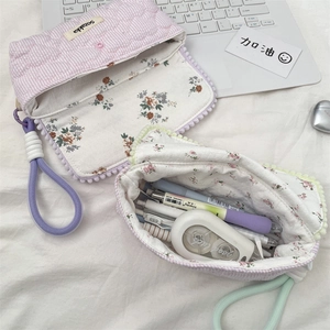 Floral and striped large capacity pencil cases with lanyards on a study desk