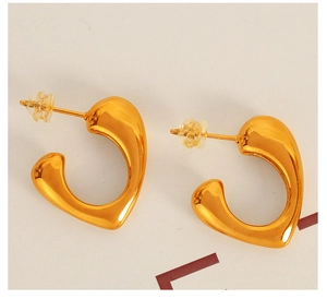 Macro detail of French style C-shaped heart earrings in a polished golden metal finish