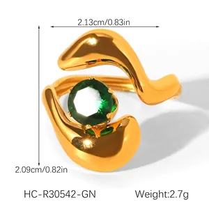 Detail of gold stainless steel ring with green zircon and asymmetric wave design