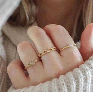 Three-piece stackable gold stainless steel rings set with zircon accents on hand