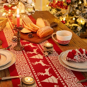 Red Christmas table runner with white reindeer and snowflake motifs on wooden table