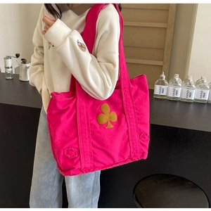 Rose red canvas tote bag with clover patch and frayed edges shown in a cafe setting