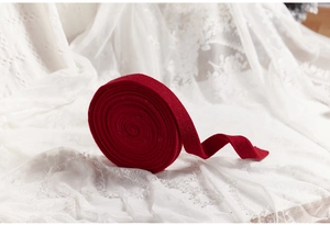 Close-up of 3cm wide dark red velvet ribbon roll on lace background for DIY Christmas crafts