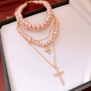 Detail of multi-layer pink pearl cross necklace with rhinestones in a luxury jewelry box