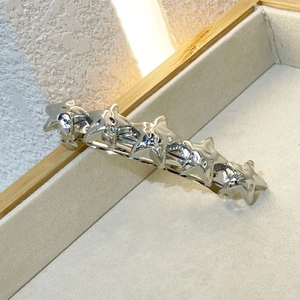 Close-up of five silver star charms on a polished metal hair clip in a wooden tray