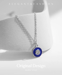 Macro shot of silver necklace featuring blue enamel evil eye pendant with clear zircon