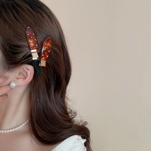 Detail of amber acrylic hair clip set with sparkling rhinestones worn by a model