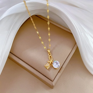 Golden rose bud necklace with clear zircon pendant on beige box and white silk