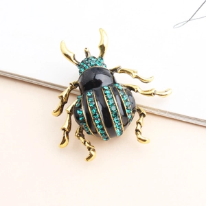 Detailed view of a vintage beetle brooch with black enamel and sparkling green crystals