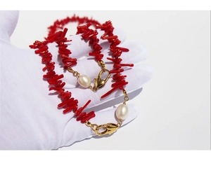 Detail of red coral branch necklace with white pearl accents and golden heart clasp