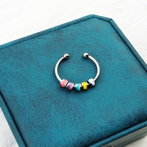 Detail of anxiety ring with colorful spinning beads on a textured green jewelry box