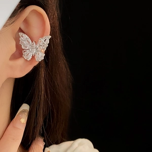 Detailed view of a silver butterfly ear cuff with sparkling zircon stones on a model