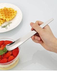 Nahaufnahme eines 304 Edelstahllöffels, der Erdbeerdessert aus einer Glasschale schöpft