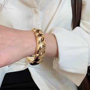 Détail d'un gros bracelet manchette torsadé doré avec finition brillante sur un mannequin