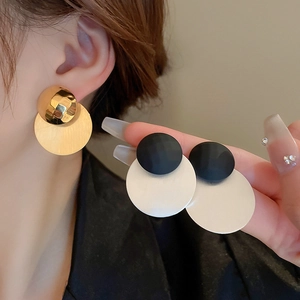 Eleganti orecchini pendenti geometrici oro e nero mostrati su modella e tenuti in mano