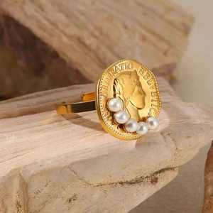 Detailed close-up of 18K gold coin ring with engraved portrait and white pearls on wood