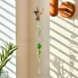 Detail of metal hummingbird suncatcher with green crystal balls and spiral stand