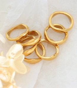 Detailed macro shot of wavy irregular 18k gold plated titanium steel rings on white paper