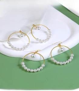 Detail of gold hoop earrings with white pearls and different fastener types