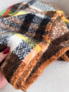 Close-up of thick plaid scarf featuring soft brushed texture and colorful fringe detail