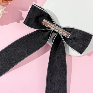Detail of black textured fabric bow hair clip with a secure metal spring fastener