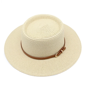 Dettaglio cappello di paglia beige con trama fine e cinturino in pelle marrone rifinito