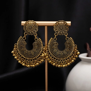 Detailed close-up of retro bohemian earrings with engraved flowers and bead tassels