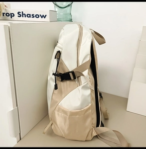 Side view of beige and white waterproof backpack showing side pockets and buckles