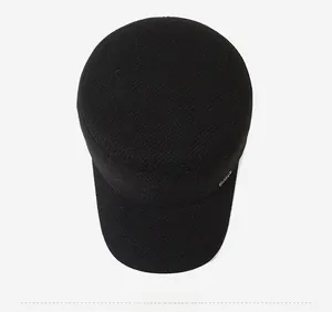 Detailed top view of a black winter wool flat top cap with fleece lining and metal tag
