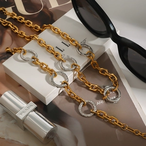 Mixed gold and silver chunky chain necklace in sleek industrial style over a magazine