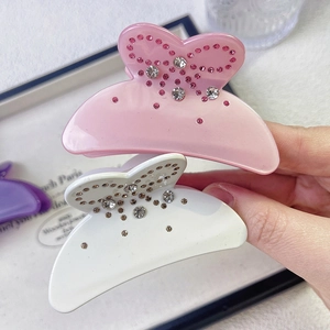 Close-up of pink and white acetate bow hair claws with sparkling rhinestone embellishments