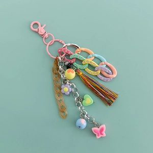Macro detail of acrylic chain keychain with cotton tassels and mixed color charms