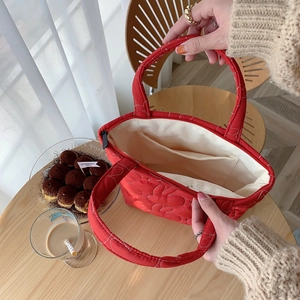 Interior detail of red quilted tote bag showing cream lining and zip pocket storage