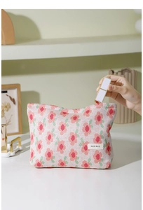 Detailed close-up of putting a lipstick into the floral knit makeup bag with soft patterns