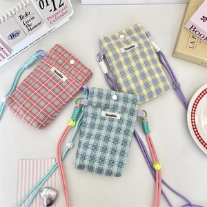 Detailed close-up of plaid fabric mobile phone pouches in pink, yellow, and blue colors