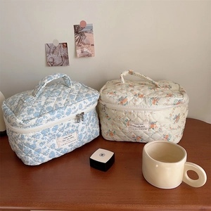 Detailed shot of quilted floral cotton makeup bags in blue and beige with zipper closure