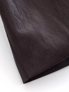 Macro shot of dark brown pebbled faux leather texture on long fashion coat