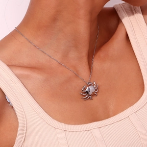 Close-up of a silver crab pendant necklace worn by a model showcasing metal detail