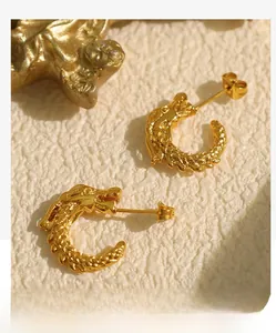 Detailed close-up of golden dragon C-shaped earrings with intricate scale texture on stone