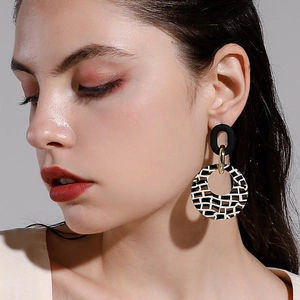 Gros plan de boucles d'oreilles géométriques à motif de grille noir et blanc sur un mannequin