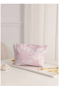 Macro detail of pink floral jacquard fabric and H & R BAG label on makeup storage bag
