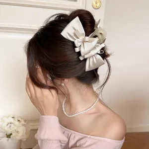 Elegant champagne gold satin bow hair claw clip shown on a model from the back view