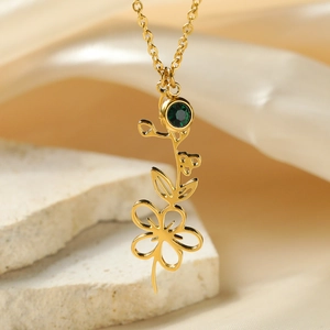 Macro shot of 18k gold plated floral pendant with a green birthstone on white stone