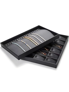 Close-up of black jewelry display trays stacked to show compartments for necklaces and bracelets