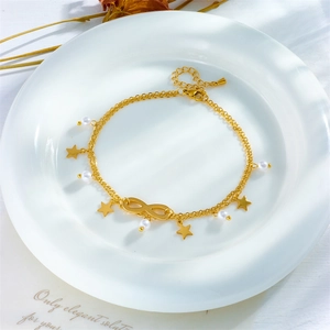 Gold layered bracelet with infinity symbol and star charms in a white ceramic dish