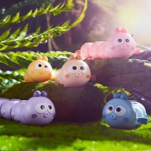 Colorful wind-up clockwork caterpillar toys crawling in a scenic forest background